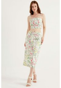 Tvådelad outfit med en kort topp och en midiklänning i ett blommönster med rosa och gula blommor på en ljus bakgrund; tyget verkar slätt.