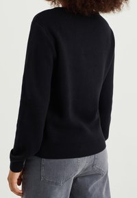 Schwarzer Strickpullover mit langen Ärmeln, Rundhalsausschnitt und geripptem Saum. Weicher Stoff, lässige Passform und schlichtes Design ohne Verzierungen.