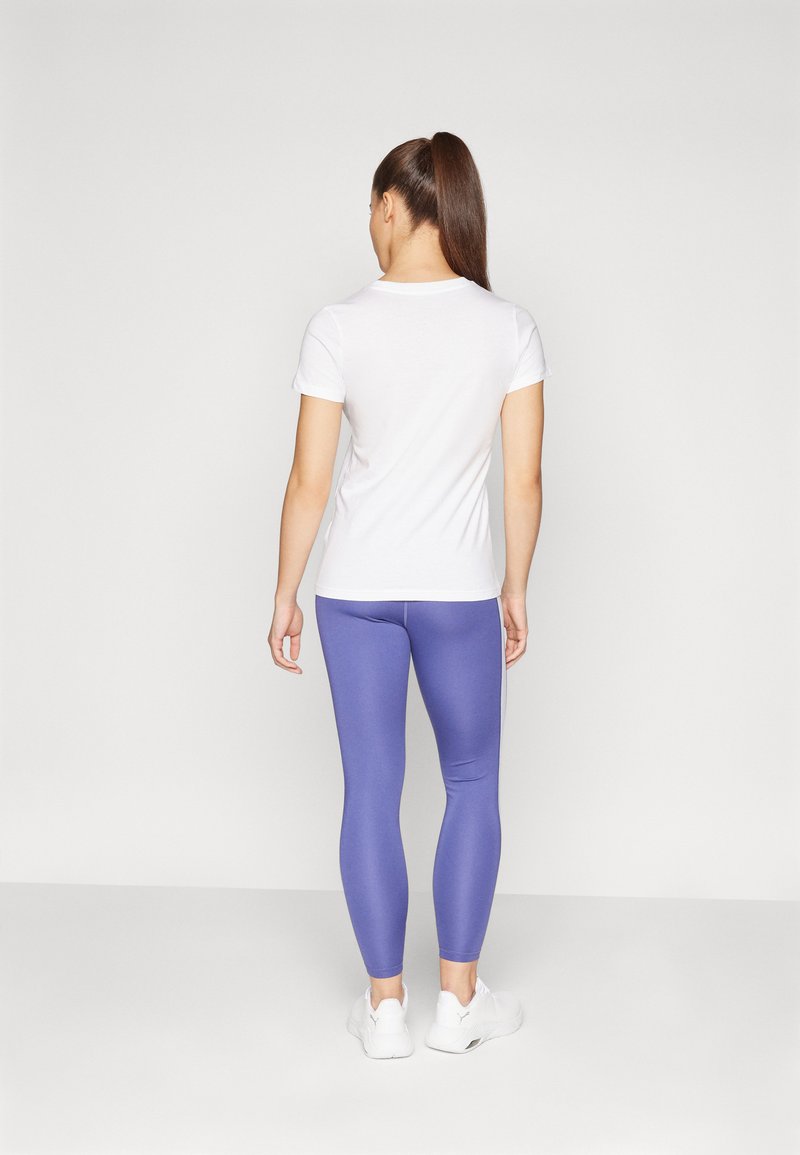 T-shirt bianco a maniche corte abbinato a leggings viola, con una texture liscia e un design aderente. Il modello indossa scarpe da ginnastica bianche.