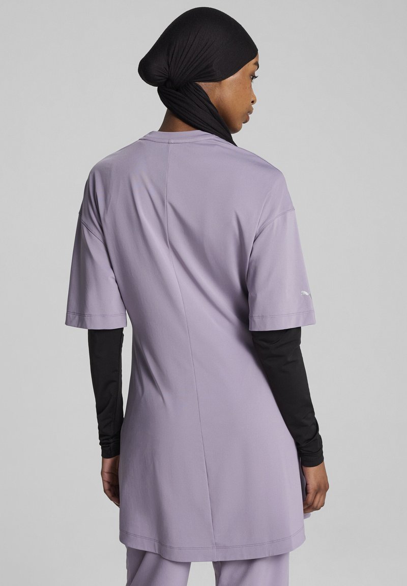 Mėtinės spalvos sporto marškiniai su trumpomis rankovėmis ir tiesiu kirpimu, derinami su juodu ilgųjų rankovių sluoksniu po jais. Lygus audinio paviršius, minimalūs akcentai.