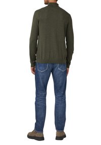 Sweter w kolorze oliwkowej zieleni z długim rękawem i prążkowanym kołnierzem, noszony z niebieskimi dżinsami i brązowymi butami, widziany od tyłu.