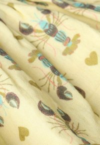 Tissu jaune clair présentant un motif répété de homards et de cœurs en bleu, marron foncé et vert olive, avec une finition douce et texturée.