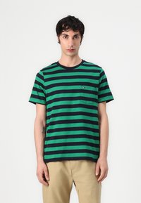T-shirt à rayures vertes et marines en coton, doté d'un col rond et d'une poche avec un petit détail de logo. Manches courtes et coupe décontractée.