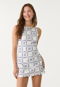 Hihaton mekko kevyestä kankaasta, valkoisella taustalla ja sinisellä geometrisella kuviolla. Kiinteä muotoilu suorahelmaisena.