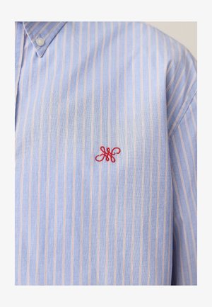 Šviesiai mėlynas juostuotas marškiniai, pagaminti iš medvilnės, su mygtukų kišeniu ir mažu raudonu siuvinėtu logotipu kairiajame krūtinės srityje.
