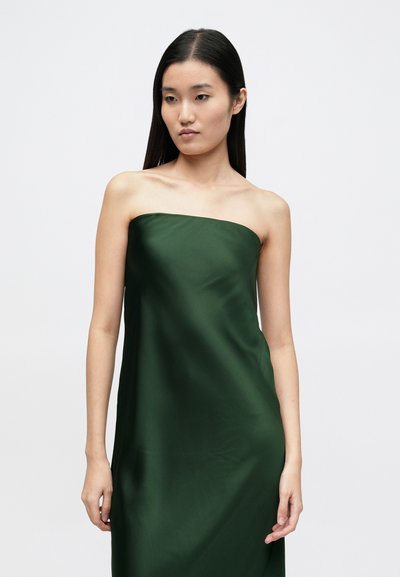 Πράσινο σατέν φόρεμα χωρίς τιράντες με ομαλή υφή, ευθεία κοπή και ρέον σχέδιο, που φτάνει μέχρι τη μέση της γάμπας, εμφανίζεται πάνω σε ουδέτερο φόντο.