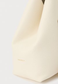 Borsa in pelle dalla trama cremosa con logo "Coccinelle" dorato discreto in basso a sinistra.