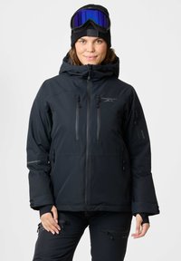Black insulated ski jacket with hood, two zippered breast pockets, adjustable cuffs, and a matte finish, worn with a black beanie and ski goggles.