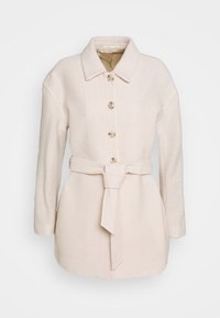 Manteau en laine couleur crème avec manches longues, boutons sur le devant et ceinture en tissu assortie nouée à la taille, présenté sur un fond uni.