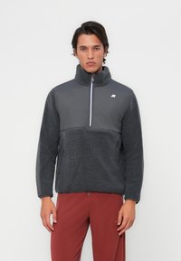 Fleece pullover in donkergrijs met een hoge kraag, halve rits en een gestructureerd lichaam. Kenmerkt zich door gladde mouwen en een logo op de borst.