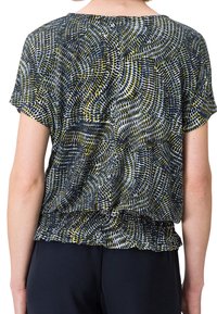 Femme portant un chemisier manches courtes avec un motif abstrait de pois circulaires bleu marine, blanc et olive, associé à un pantalon noir, vue de dos.