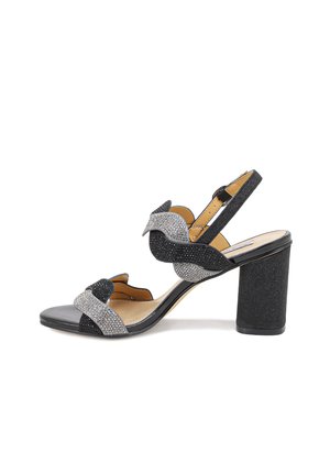 Sandal con tacco alto nero e argento con un ampio tacco a blocco. Presenta cinturini testurizzati, un nodo decorativo e accenti brillanti.