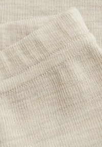 Beiger Strickstoff mit weicher Textur, der horizontale Rippungen und einen umgeschlagenen Saum entlang einer Kante aufweist. Eine Nahaufnahme hebt die feinen Garndetails hervor.