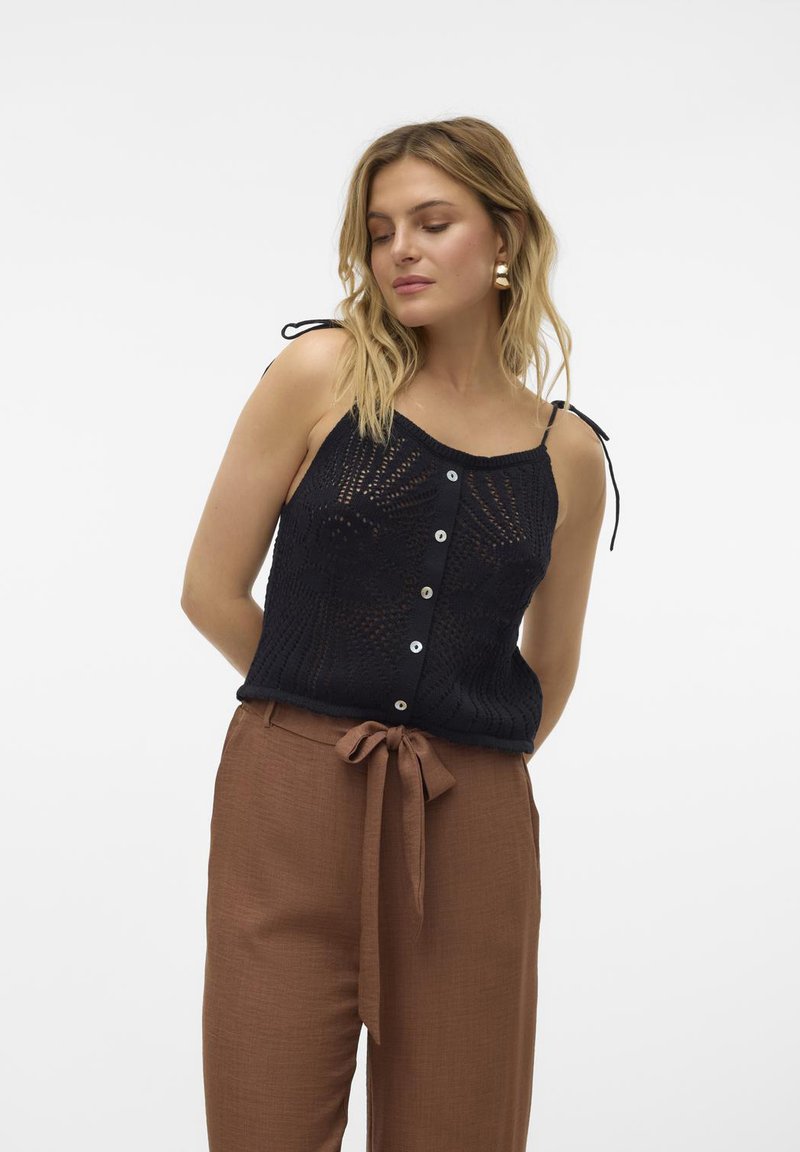 Top de punto negro sin mangas con detalles de botones y tirantes ajustables con lazo, combinado con pantalones marrones de cintura alta con un acento de cintura atada.