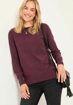 Burgundy knit sweater with textured side detailing, round neckline, and ribbed cuffs. Paired with black pants and a small black crossbody bag.