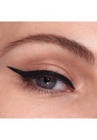 Gros plan sur un œil avec un eyeliner noir appliqué avec précision qui met en valeur la paupière. L'iris est bleu avec des reflets gris. La texture de la peau est lisse.