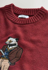 Czerwony sweter z dzianiny z ilustracją pandy w okularach i marynarce. Żebrowany kołnierz, miękka faktura i kolorowe wstawki w całej powierzchni.