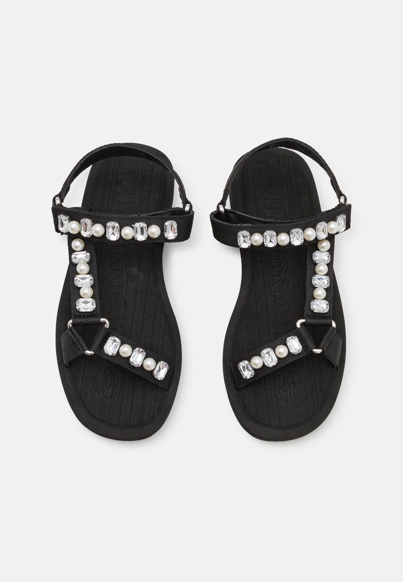Sandales noires avec une semelle texturée, des brides ajustables, et embellies de pierres claires et de perles synthétiques le long des brides.