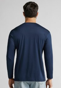 T-shirt a maniche lunghe di colore blu navy realizzato in tessuto liscio, con scollo rotondo e un design semplice senza motivi o accenti visibili.