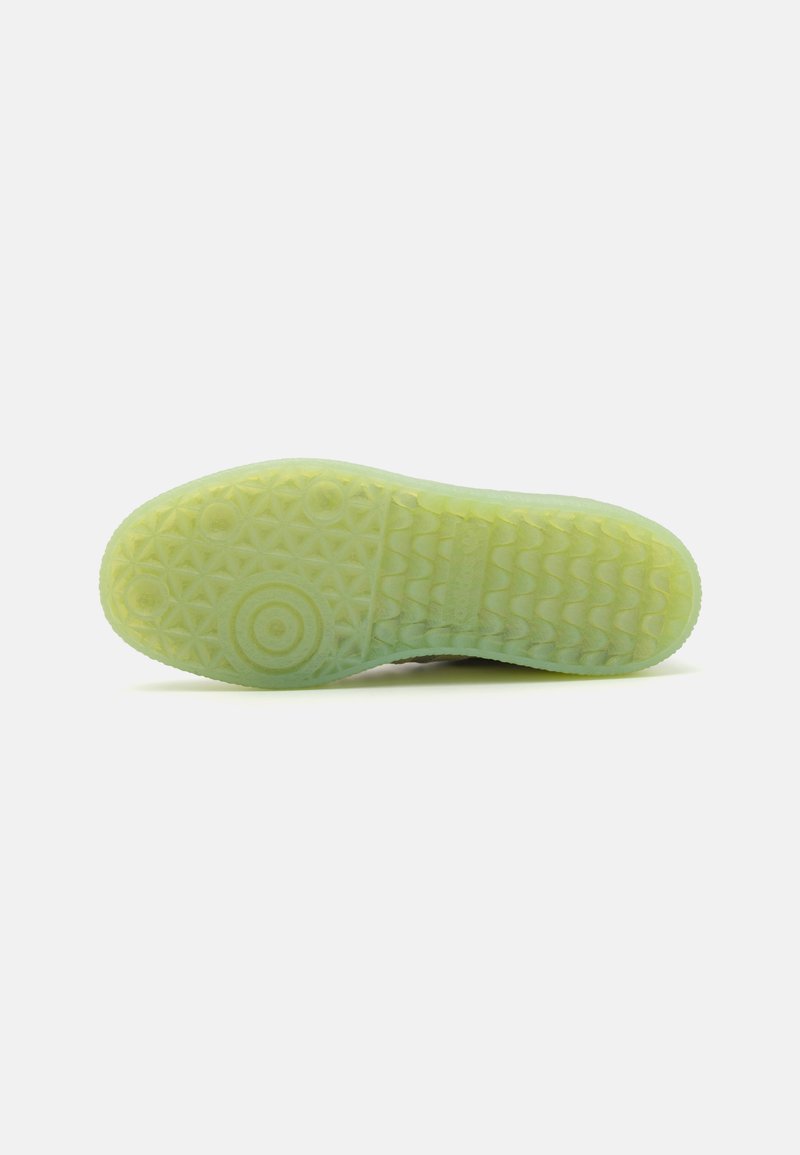 Suola in gomma verde translucida con un motivo geometrico testurizzato, caratterizzata da forme circolari e stellari per una migliore aderenza e trazione.