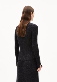 Maglione nero a coste con maniche lunghe, caratterizzato da un design aderente, aperture laterali ai polsini e un motivo texturizzato a macchie.
