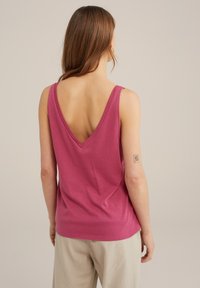 Ärmlös V-ringad linne i en solid rosa färg. Mjuk tyg med en lös passform, med en låg ryggdesign. Tillsammans med ljusa byxor.