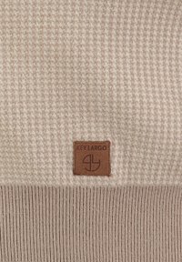 Beige gebreide trui met textuurpatroon en geribbelde zoom. Voorzien van een bruine leren logo patch met "KEY LARGO" in reliëflettertype.