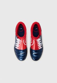 Red and navy sneakers featuring a smooth synthetic upper, white laces, and a prominent Nike logo on the side.