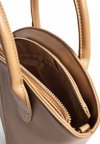 Tan leather tote bag with two top handles, featuring a main compartment and a zippered pocket. Smooth texture and contrasting stitching detail.
