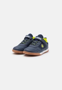 Dunkelblaue Sportschuhe mit strukturiertem Synthetik-Obermaterial, grünen Schnürsenkeln, Klettverschluss, Gummisohle und JAKO-Logo auf der Zunge.