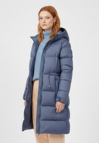 Marineblauwe donsjas met capuchon, met een doorgestikt ontwerp, ritssluiting aan de voorkant, elastische manchetten en een taillekoord voor een verstelbare pasvorm.