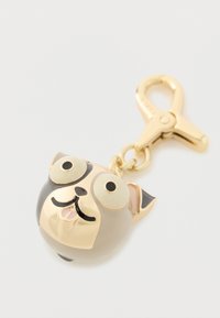 Kulta-musta koiranpääavaimenperä, jossa suuret silmät ja avoin suu, kiinnitetty kultaisella lukkokoukkulukolla valkoisella taustalla.