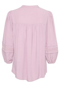 Blusa rosa chiaro con un motivo testurizzato, colletto rotondo e maniche svasate con dettagli in pizzo. L'orlo è curvo sul retro.
