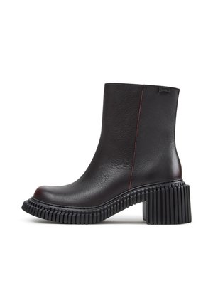 Bottine en cuir noir avec semelle épaisse crantée et talon bloc, couture latérale et petite étiquette en tissu de la marque près du haut.