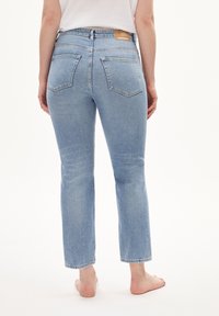 Jean en denim bleu clair avec une coupe droite, comprenant deux poches arrière et une étiquette marron au niveau de la taille. Aucune usure visible.