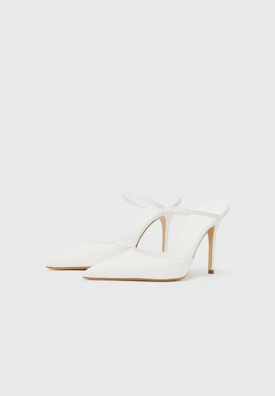 Bílé špičaté lodičky na podpatku se štíhlým designem, tenkým páskem kolem kotníku a stiletto podpatkem. Hladká textura, minimalistický styl.