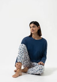Haut à manches longues bleu marine associé à un pantalon blanc orné d'un imprimé floral aux tons bleus et roses. Tissu doux, coupe décontractée et motif à motifs.