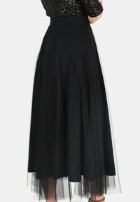 Czarna, zwiewna spódnica midi z gładką, dopasowaną talią i warstwą tiulu, charakteryzująca się subtelnym blaskiem i lekką teksturą.