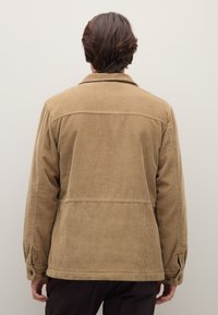 Giacca marrone in velluto a coste con colletto, polsini con bottoni e esterno testurizzato. La vista posteriore mostra un design semplice e a taglio dritto.