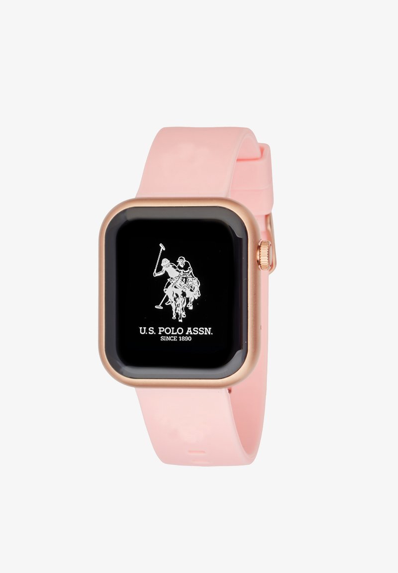 Montre connectée carrée avec un écran noir, un cadre en or rose et un bracelet en silicone rose. Présente le logo U.S. Polo Assn. en blanc.