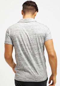 Grijze polo met korte mouwen, voorzien van een gestructureerd, gemêleerd patroon. Heeft een klassieke kraag en een slim-fit ontwerp met een rechte snit.