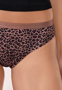 Bikini w kolorze leopardziego nadruku wykonany z gładkiego, elastycznego materiału. Posiada błyszczący, elastyczny pas w kolorze różowego złota.