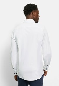 Weißes Langarmhemd mit schmaler Passform, ausgestattet mit einem spitzen Kragen, Knopfdetails an den Bündchen und einem glatten, leichten Stoff.