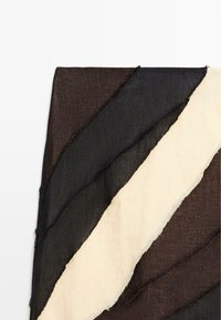 Stoff mit diagonalen Streifen in Dunkelbraun, Schwarz und Offwhite, zeigt ausgefranste Kanten und strukturierte Webung.