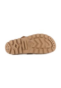 Suola della scarpa con un design robusto e strutturato in gomma marrone chiaro, caratterizzata da scanalature profonde e aperture circolari per una presa e flessibilità ottimali.