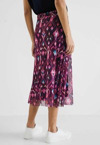 Plisserad midikjol i ett flerfärgat geometriskt mönster med rosa, lila och blå nyanser, försedd med ett elastiskt linning och lätt material.