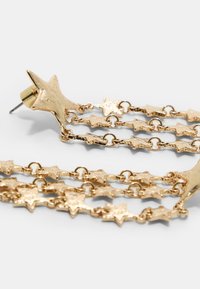 Ohrringe in Goldoptik in Sternform, die ein mehrkettiges Design mit strukturierten fünfzackigen Sternen aufweisen. Sie verfügen über einen Steckverschluss.