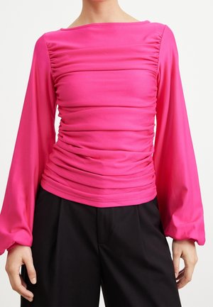 Top aderente rosa con maniche lunghe e svasate e texture arricciata sulla parte del torso. Il materiale appare liscio e elastico, con un collo a barca.