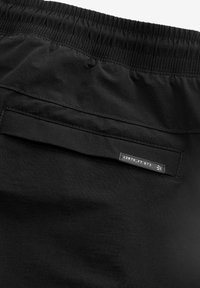 Sorte shorts med elastisk talje, der har en baglomme. Materialet er glat og ensartet med en subtil glans.