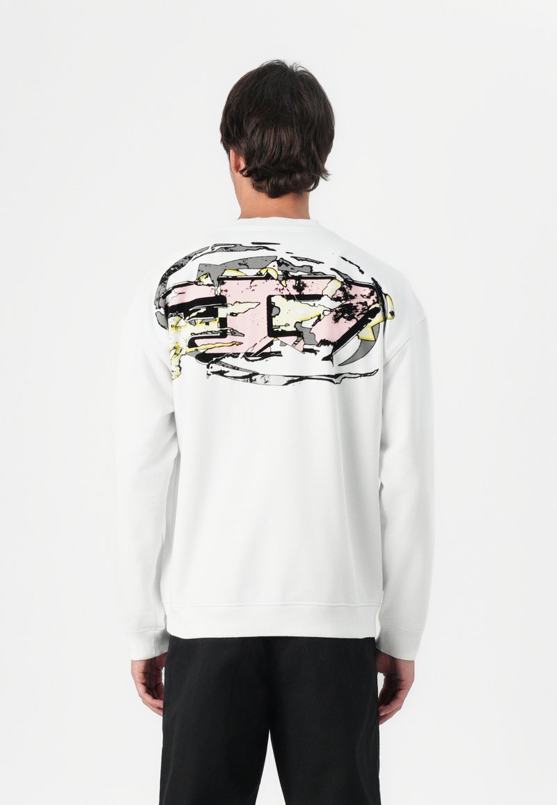 Sweatshirt branco com uma grande ilustração abstrata em rosa, amarelo e cinza nas costas. Apresenta mangas longas e punhos e bainha canelados.